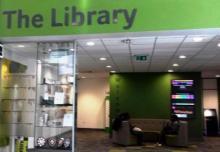 Interior view of Univerdity of Huddersfield, there is signage and bookshelves in view.