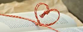 open book with red and white string curled into a heart shape.