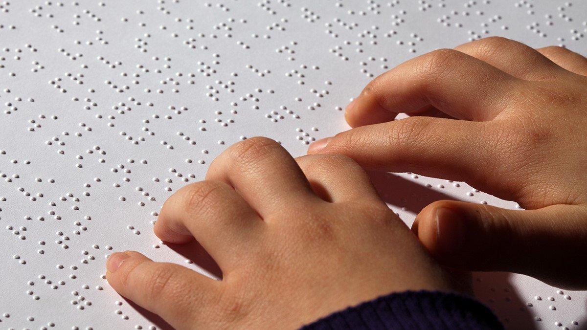 braille text with hand of a child scanning it