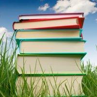 Colourful stack of books against a blue sky.