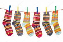 Multicoloured odd stripy socks on a washing line.