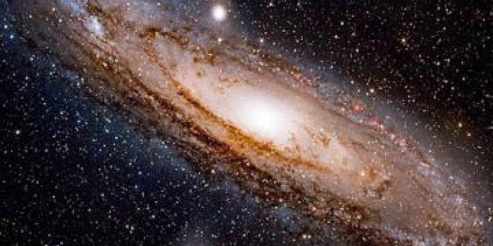 The Andromeda galaxy shown as dark space with stars and a swirling mass or ball of lights at the centre.