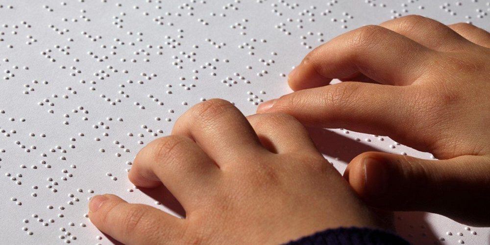 Embossed braille page with hands scanning the page.