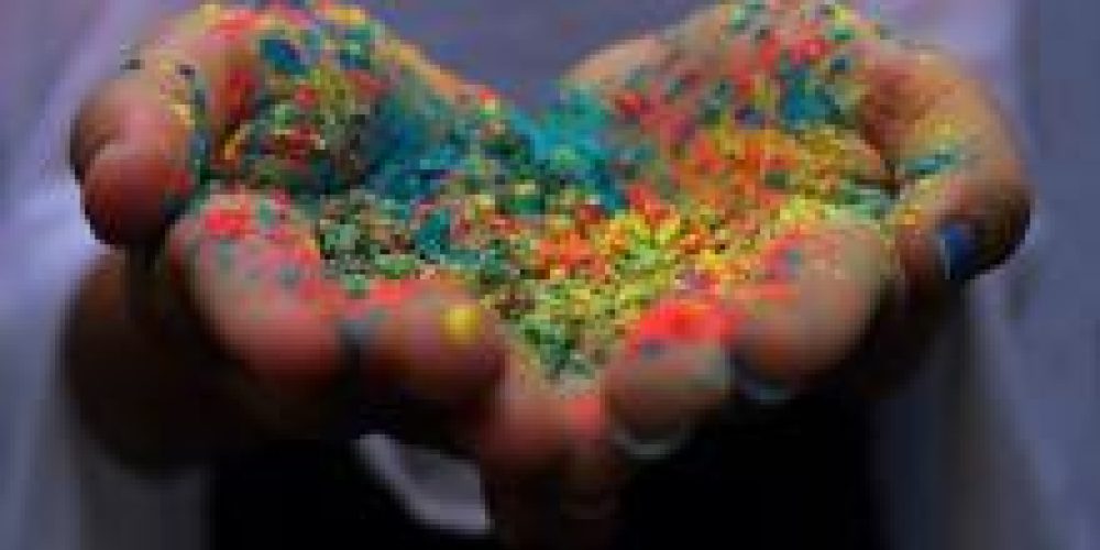 open cupped hands in shape of a heart holding powder in assorted rainbow colours