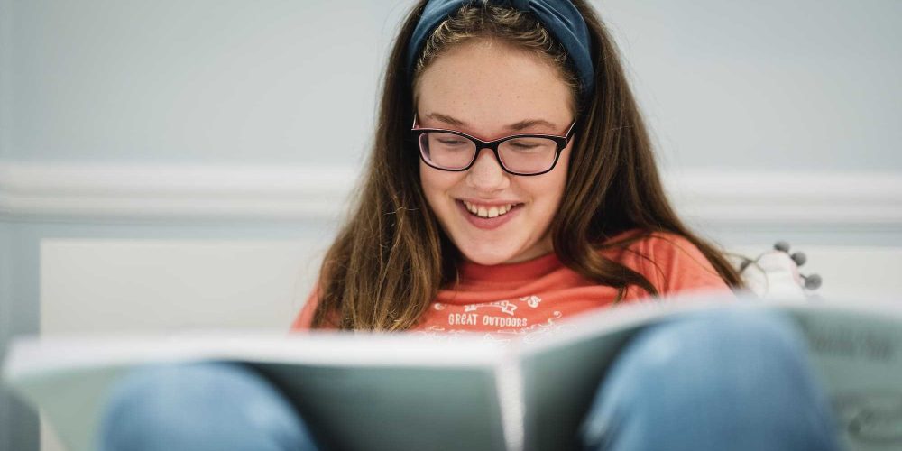 a young girl sat with a large print book in her lap