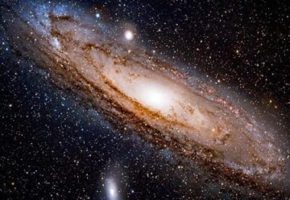 The Andromeda galaxy shown as dark space with stars and a swirling mass or ball of lights at the centre.