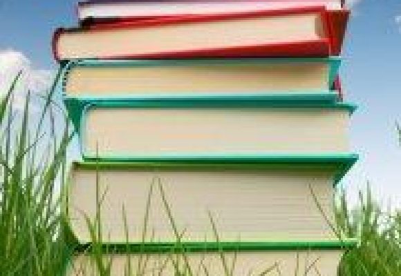 Colourful stack of books against a blue sky.