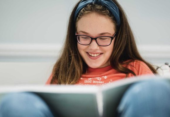 a young girl sat with a large print book in her lap